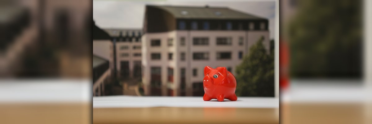 Red piggy bank in foreground, blurred city hall in background